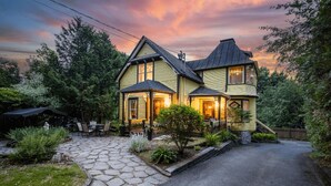 A two-story house with a stone pathway leading to the entrance, surrounded by greenery. - Victorian inn dating from 1864 with spa - sleeps 18 (WATERLOO)
