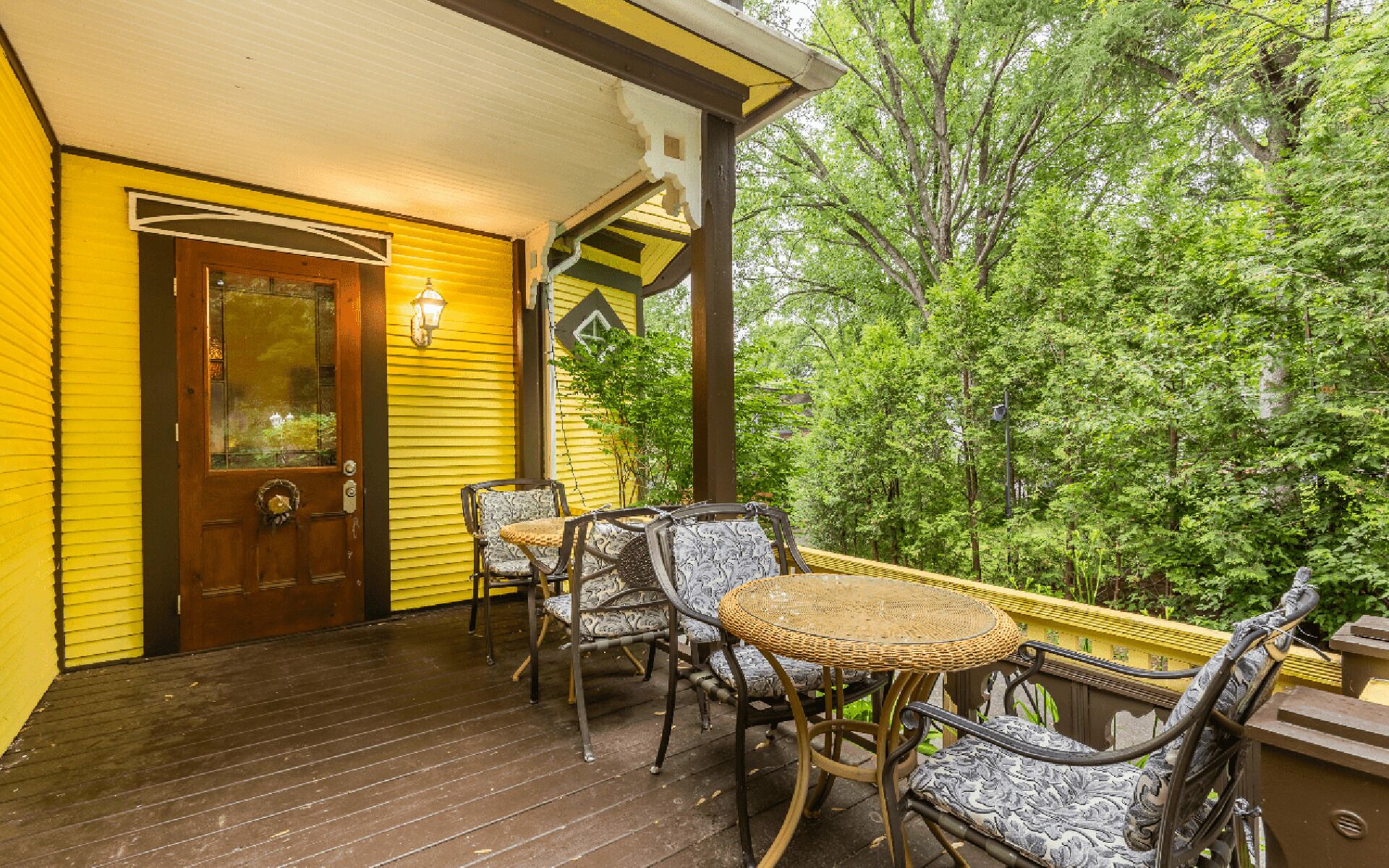 A wooden deck with wicker furniture and a glass door.