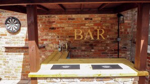 A brick wall with a dartboard and a bar sign. - Wood Farm Cottage (Boston)