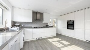 A modern kitchen with white cabinetry, a built-in stove, and a large oven. - The Willow - Home with modern facilities in the outstandingly beautiful Surrey (Woking)