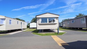 A row of mobile homes with a central structure featuring a small porch and a window. - Willerby Aurora B14 (Abergele)