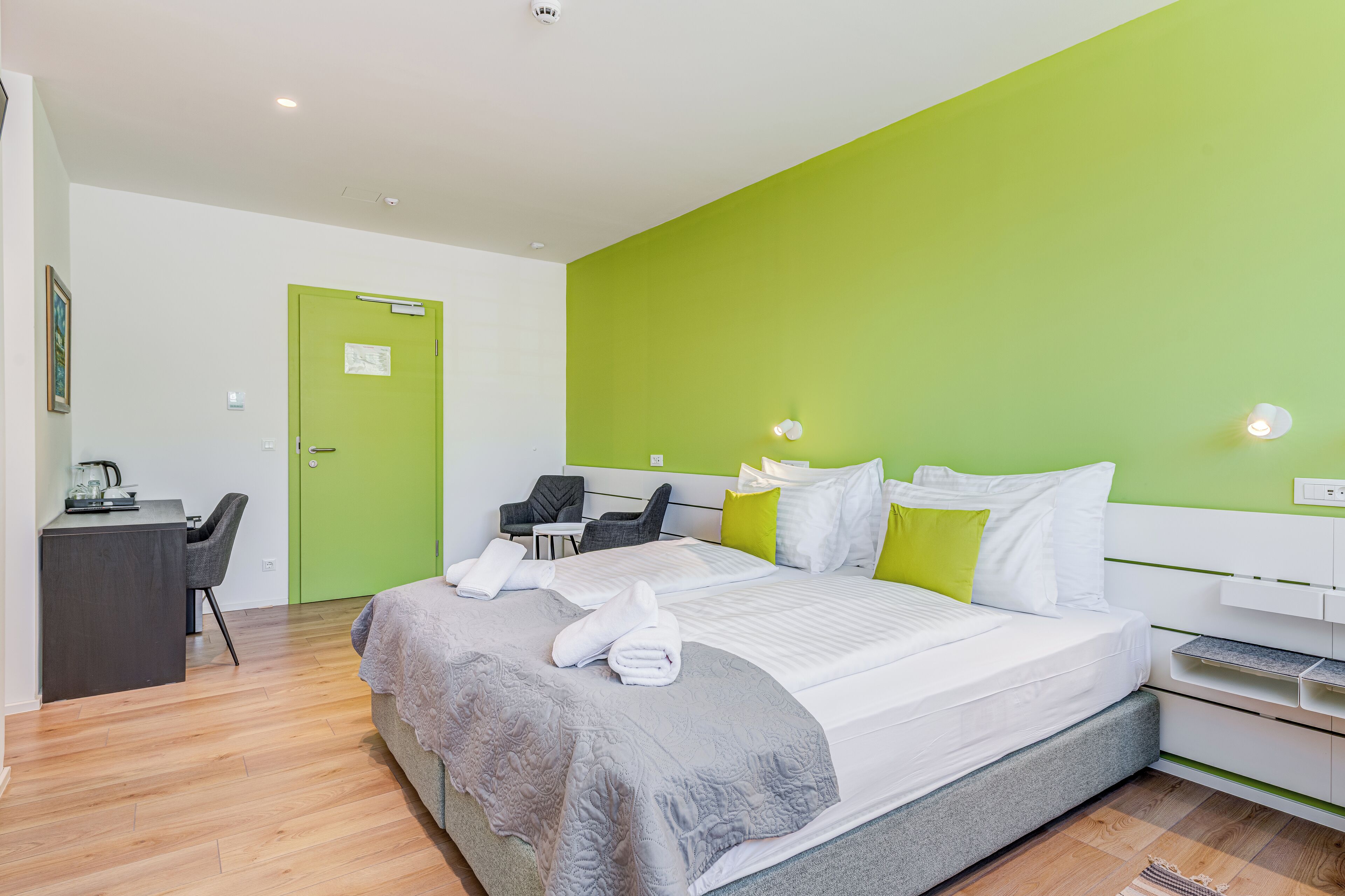 A modern hotel room with a large bed, a desk, and a chair.