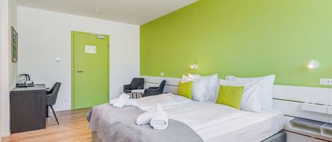 A modern hotel room with a large bed, a desk, and a chair.