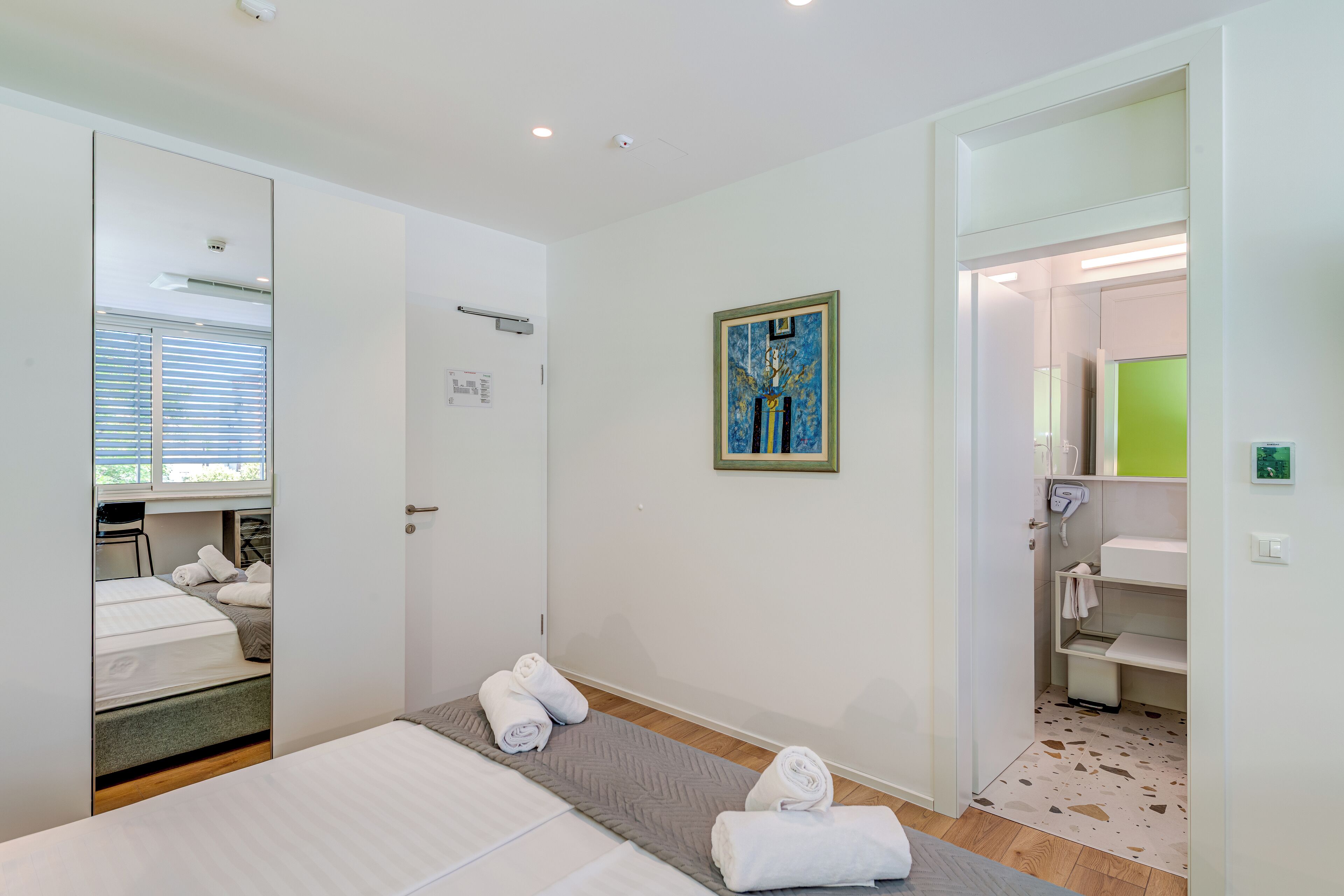 A hotel room with a bed, a bathroom, and a small desk area.
