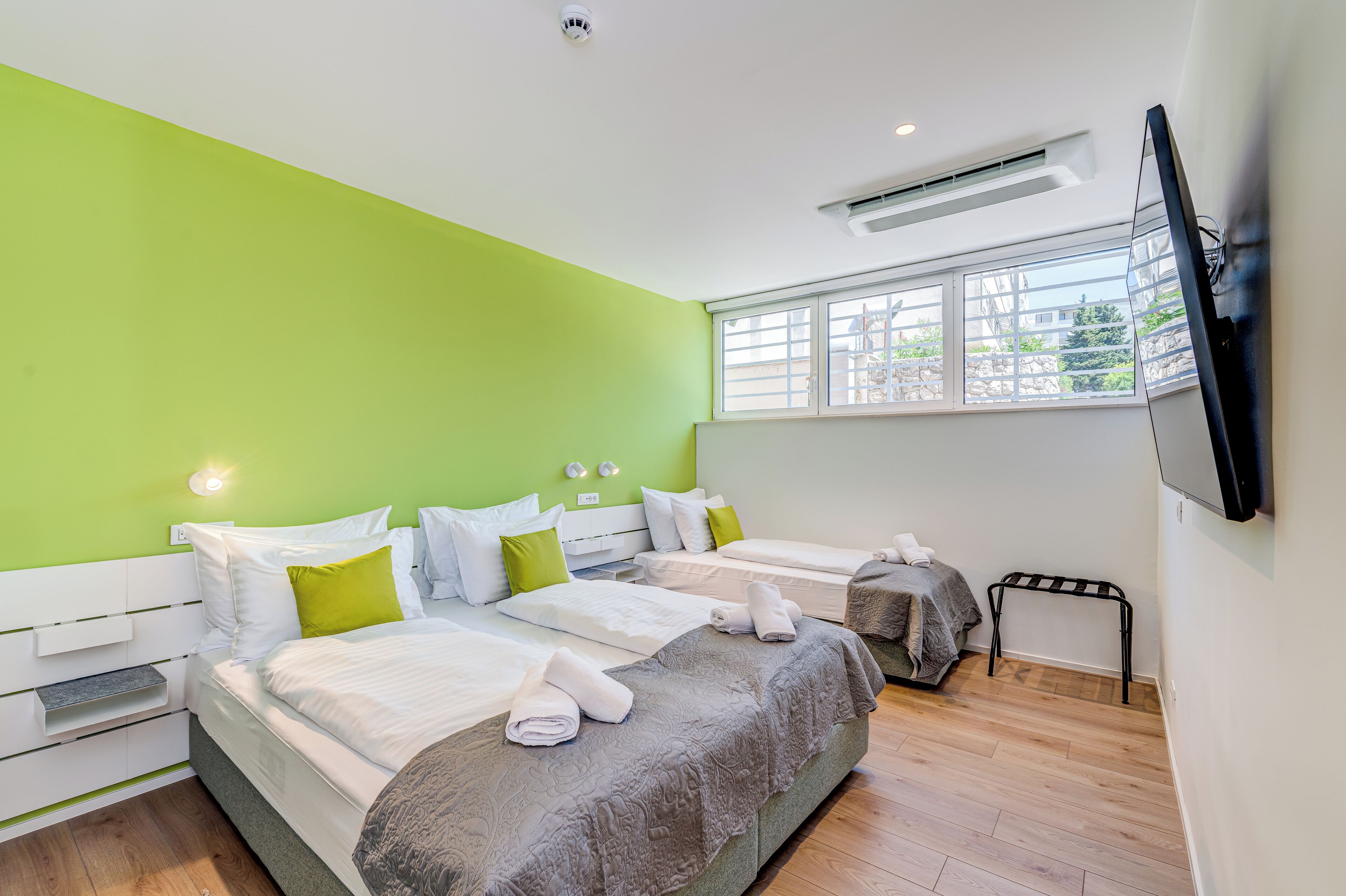 Une chambre d’hôtel moderne avec deux lits, un téléviseur à écran plat, une fenêtre donnant sur un beau paysage et une petite table.