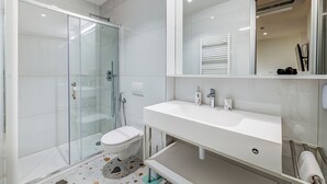 Une salle de bain moderne avec une douche à parois de verre, un lavabo blanc et un grand miroir.