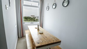 Una habitación con una mesa de madera, un ventanal con cortinas y tres espejos en la pared.