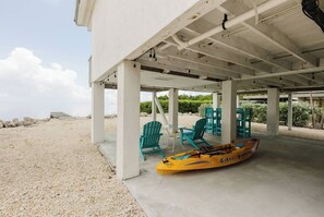 Un'area salotto all'aperto coperta, con sedie e un kayak.