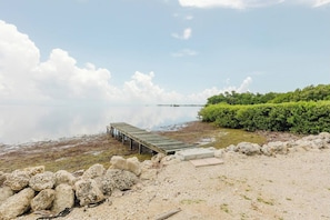 A calm waterfront with a wooden pier extending into the water, surrounded by rocks and greenery. - Private waterfront escape! Open water views & kayaks. Come sail away (Marathon)