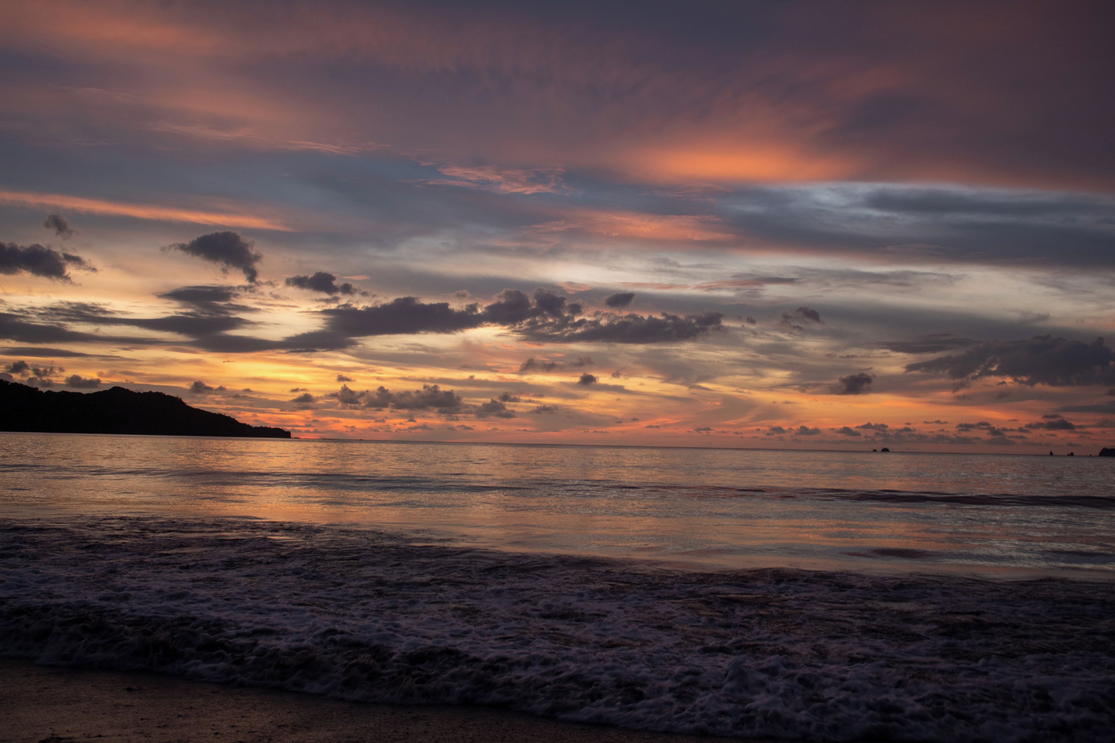 A beach with waves at sunset.