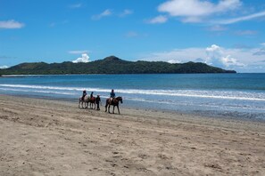 A beach with a group of people riding horses. - Hotel Brasilito (Cabo Velas)