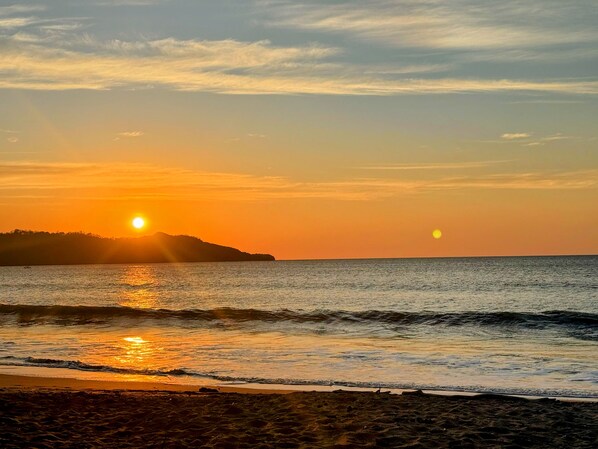 A beach at sunset with the sun reflecting on the water. - Hotel Brasilito (Cabo Velas)
