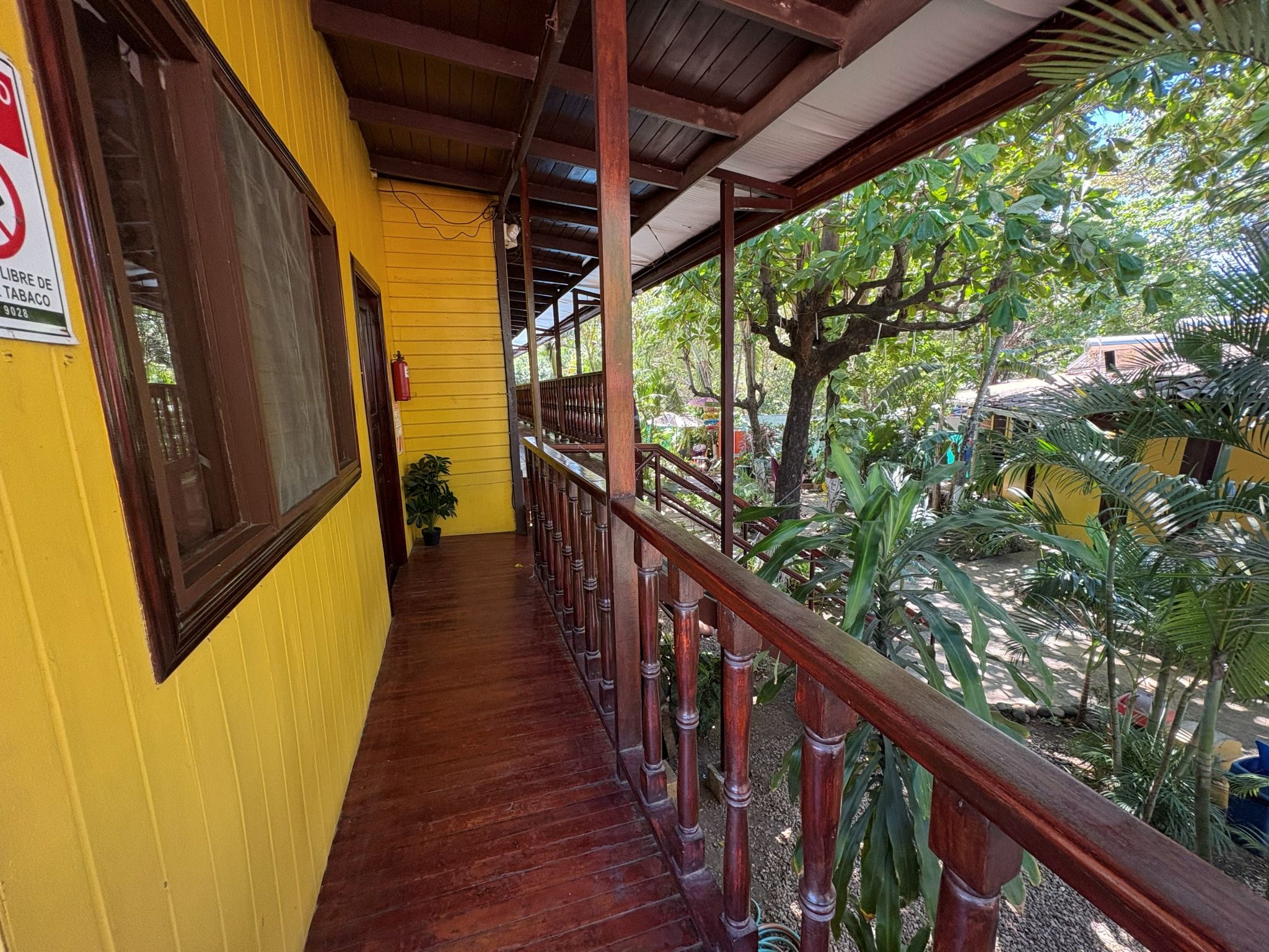 A covered outdoor area with a wooden railing, yellow walls, and a fire extinguisher.