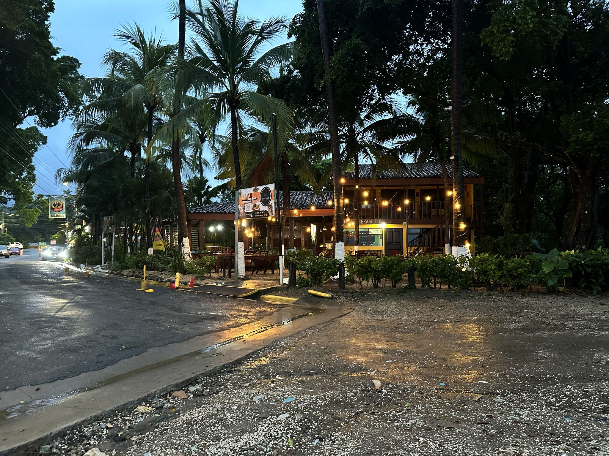 A building with a tiled roof, surrounded by palm trees, and a sign indicating a restaurant.