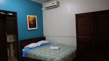 Quarto com cama, ar-condicionado na parede, pia e porta.