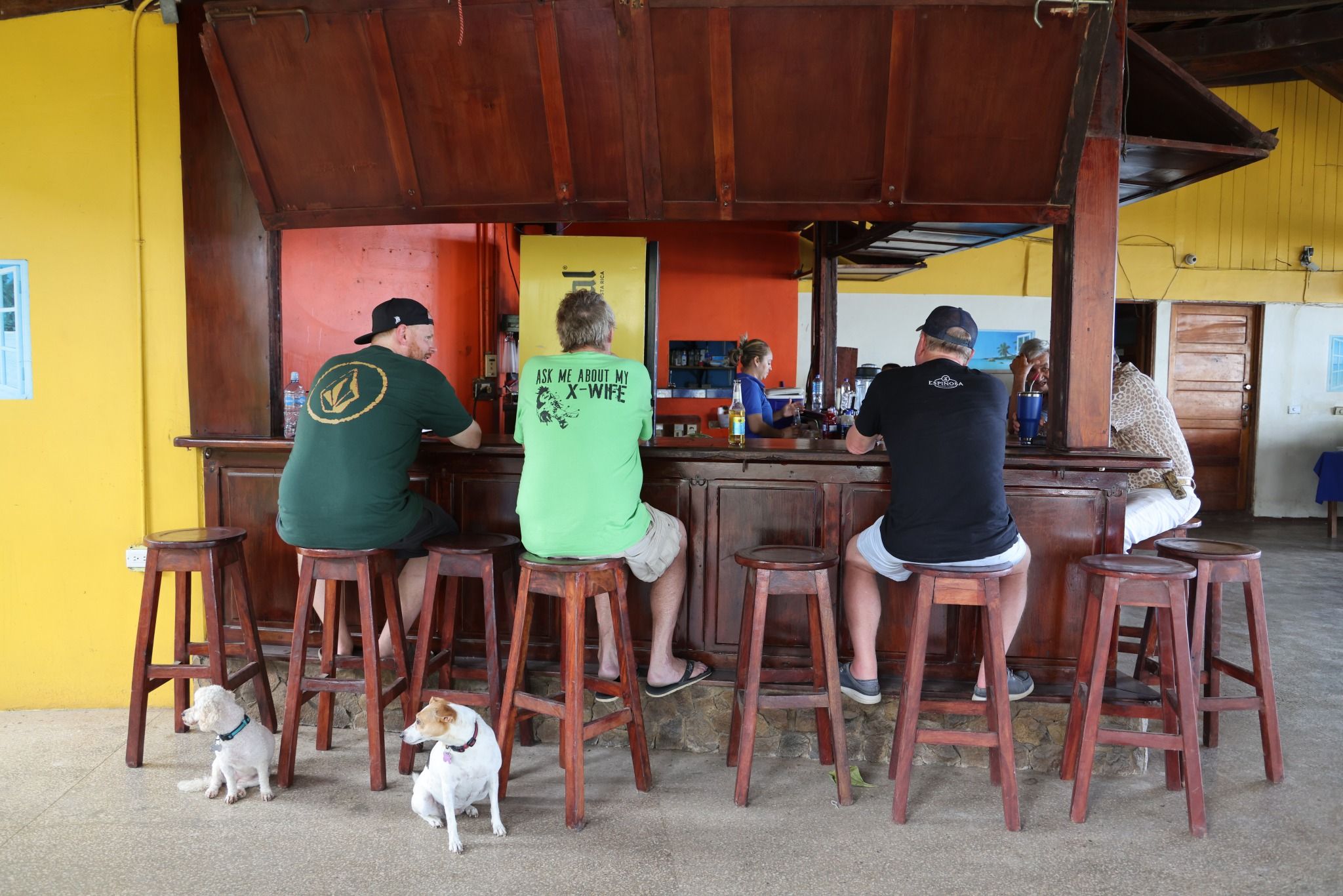 A bar area with wooden stools and a yellow wall.