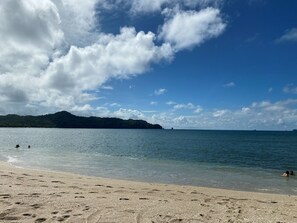 Ein Strand mit klarem Wasser, sandigem Ufer und einem entfernten Berg.