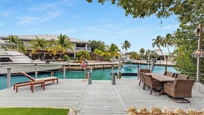A marina with boats docked, a pool area with lounge chairs, and a wooden deck.