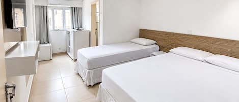 A hotel room with two beds, a desk, a mirror, a TV, and a window with curtains.