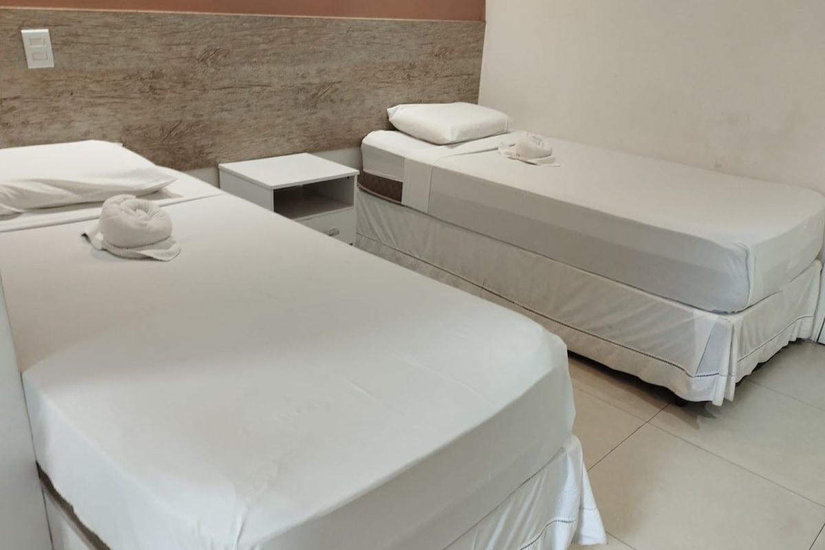 Ein Hotelzimmer mit zwei Einzelbetten, einem Nachttisch und einem an der Wand befestigten Lichtschalter.