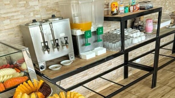 Een ontbijtbuffet met diverse soorten fruit, een koffieapparaat en een sapautomaat.