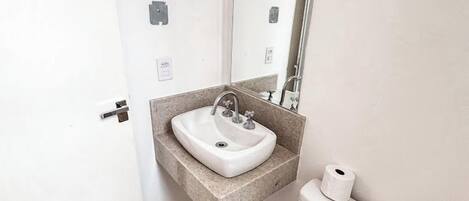Un baño pequeño con un lavabo blanco, un inodoro y un espejo sobre el lavabo.