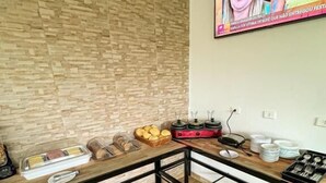 Een moderne woonkamer met een houten vloer, een grote tv aan de muur en een eettafel met verschillende soorten eten en bestek.