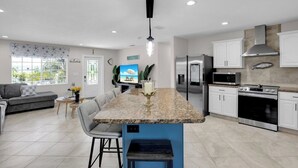 Una cocina moderna con una isla central, electrodomésticos de acero inoxidable y un comedor con sofá y sillas.