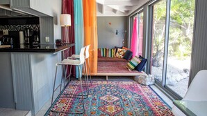 A modern kitchen with a bar area, a seating area with colorful cushions, and a large window with a view of the outdoors. - Seaside Dream House 3bed/2bath single family with open water views (Marathon)