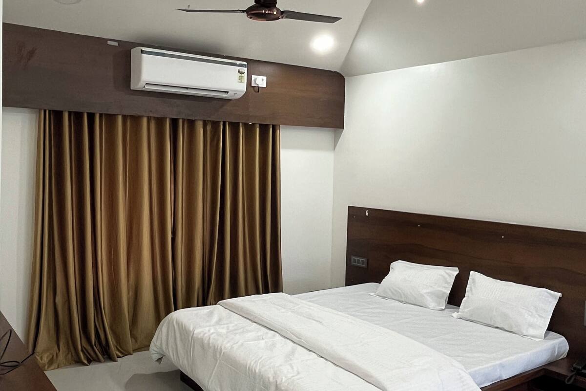 Ein modernes Hotelzimmer mit einem großen Bett, einer Klimaanlage, einem Deckenventilator und Blick auf die Stadt.