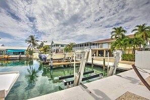 Ein Yachthafen mit vertäuten Booten, ein Schwimmbad und ein Gebäude mit einem Balkon mit Blick auf das Wasser.