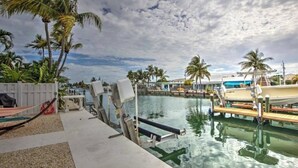 A pool area with lounge chairs, a dock, and palm trees. - Splash Into Me! New 3 BR in Key Colony w/ dockage + private pool (KEY COLONY BEACH)