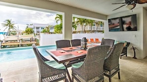 A poolside area with wicker furniture, a table, and a ceiling fan. - Splash Into Me! New 3 BR in Key Colony w/ dockage + private pool (KEY COLONY BEACH)
