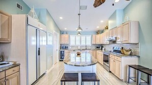 A modern kitchen with a central island, stainless steel appliances, and light wood cabinetry. - Splash Into Me! New 3 BR in Key Colony w/ dockage + private pool (KEY COLONY BEACH)