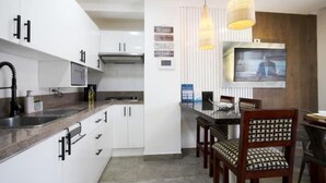 Una cocina moderna con armarios blancos, microondas y comedor con sillas de madera y una mesa.