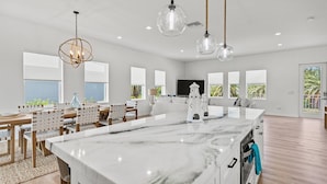 Cozinha ampla com bancada de mármore, luminárias pendentes e uma ilha grande.