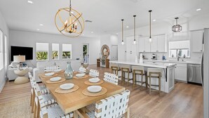 Uma cozinha moderna com armários brancos, uma ilha central e iluminação pendente.