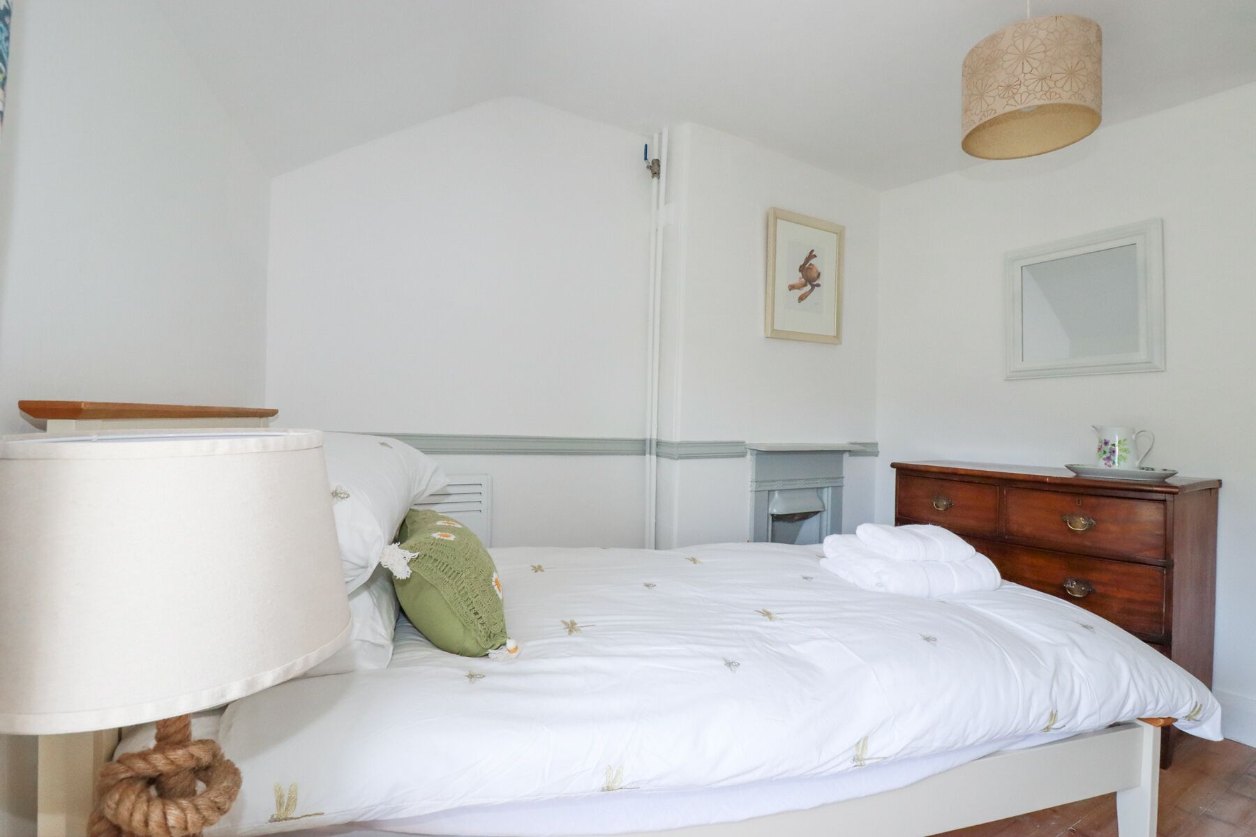 Un dormitorio con una cama, un aparador, una lámpara y un cuadro en la pared.