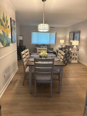 Uma sala de jantar com uma mesa de madeira, cadeiras e um lustre.