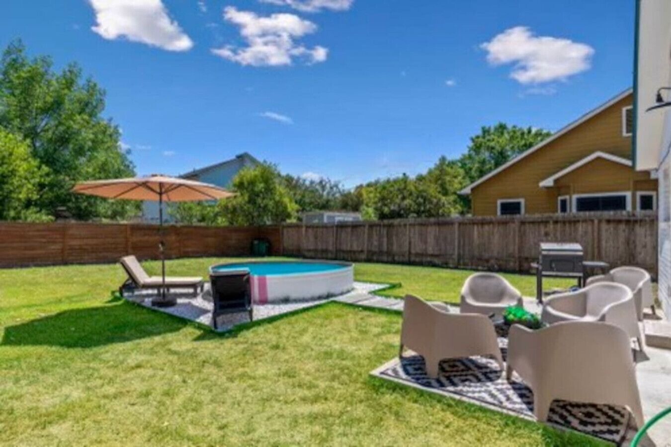 En baghave med swimmingpool, liggestole og grillområde.