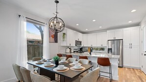 A modern kitchen with white cabinets, a central island, and a dining area with a table set for four.