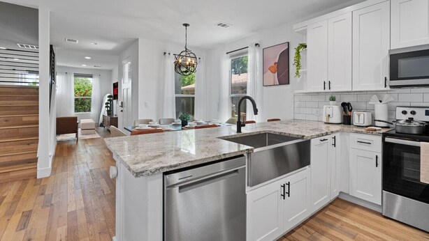 A modern kitchen with white cabinets, stainless steel appliances, and a granite countertop.