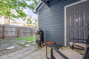 A backyard with a barbecue grill, a wooden fence, and a door.