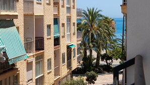 Ein mehrgeschossiges Gebäude mit Balkonen, einer Palme und Blick aufs Meer.