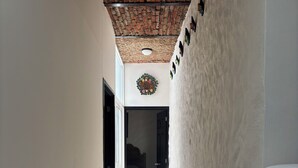 A narrow hallway with a tiled floor, a brick ceiling, and a door leading to a bedroom.