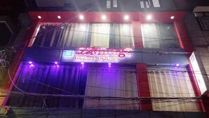 Um edifício com um letreiro de neon para 'Semirage Guest House' e uma placa para 'Halal Pizza Fun' abaixo.