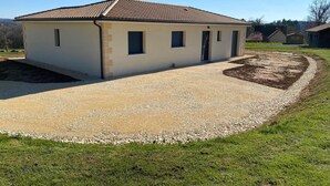 A single-story building with a tiled roof, a gravel driveway, and a landscaped garden area. - Air-conditioned country house for 6 people in Périgord Noir (Hautefort)