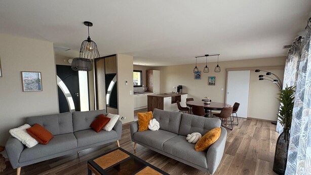 A modern living room with two grey sofas, a coffee table, and a dining area with a table and chairs. - Air-conditioned country house for 6 people in Périgord Noir (Hautefort)