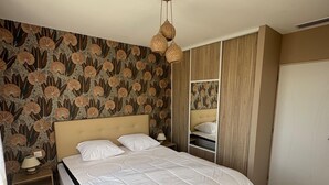 A bedroom with a large bed, wooden flooring, a patterned wallpaper, and a wardrobe. - Air-conditioned country house for 6 people in Périgord Noir (Hautefort)