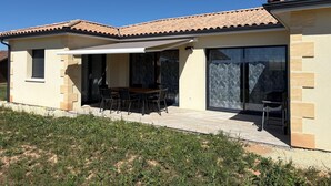 A modern house with a patio, a dining area, and large sliding glass doors. - Air-conditioned country house for 6 people in Périgord Noir (Hautefort)